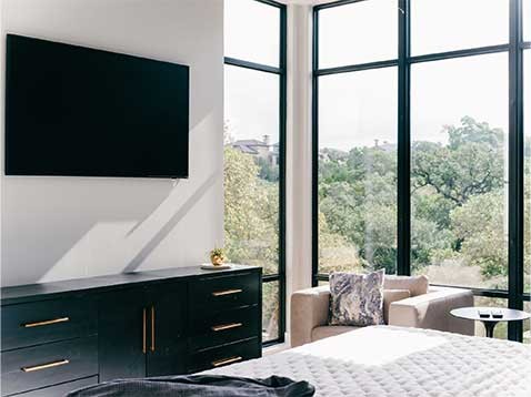 Modern bedroom with large windows and a mounted tv